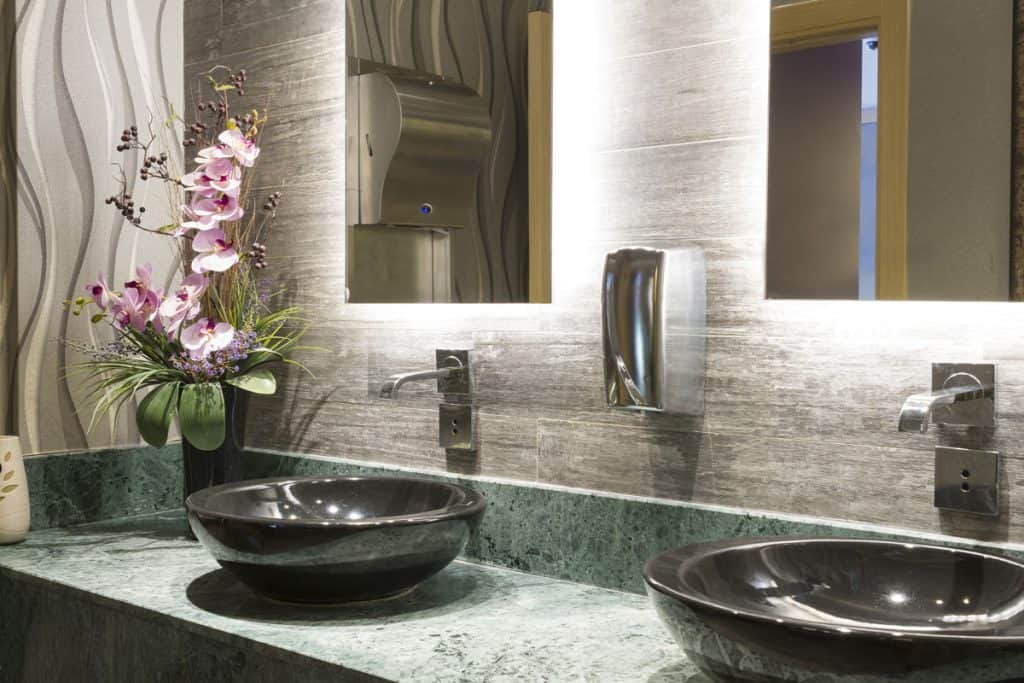 Luxurious interior of a modern bathroom with granite countertop and marble sinks and a huge mirror
