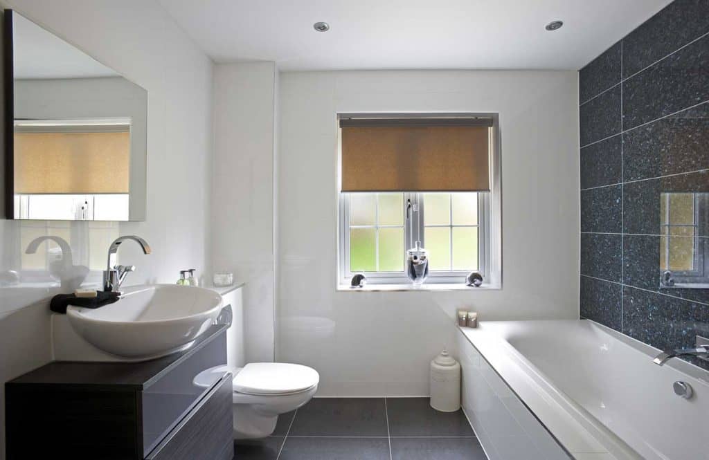 Luxury bathroom with bathtub, large mirror over sink and wall-hung elongated toilet