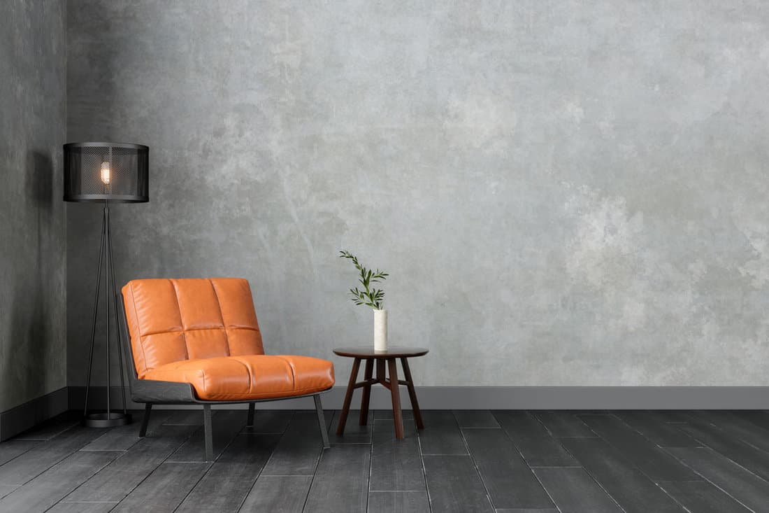 Modern Interior With Orange Colored Leather Armchair, Sconce, Coffee Table And Gray Wall