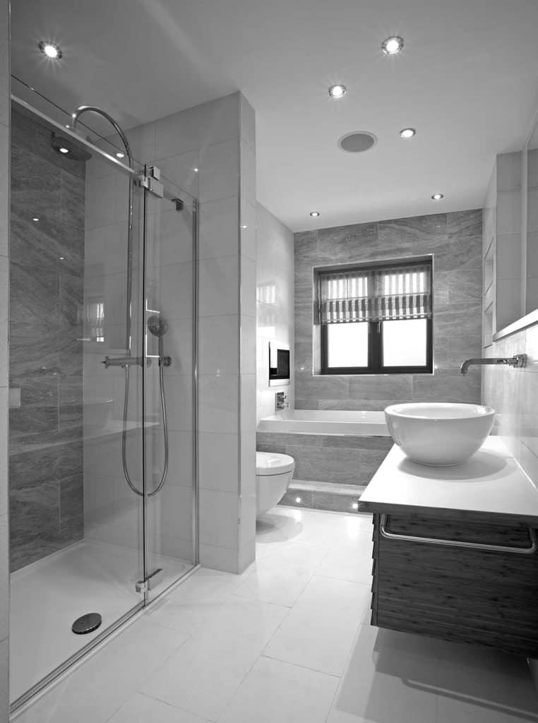 Intérieur de salle de bain moderne avec télévision au-dessus de la baignoire, sol en marbre et carrelage et douche avec porte en verre