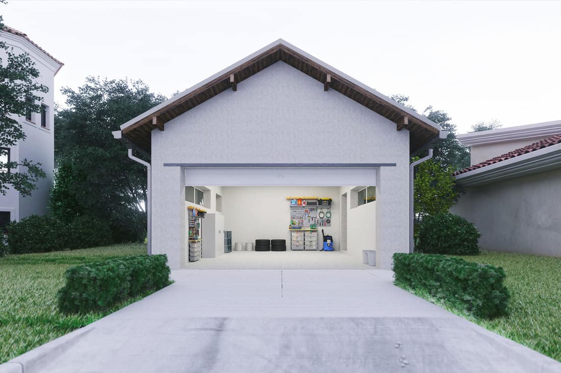 Porte ouverte d'un garage moderne avec une allée en béton dans le quartier urbain, une porte de garage doit-elle s'ouvrir à l'intérieur ou à l'extérieur ?