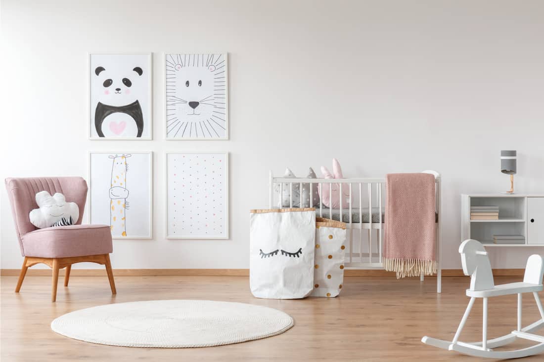 Pink armchair in child's room, crib, rocking horse, framed photos. A room that grows with her.