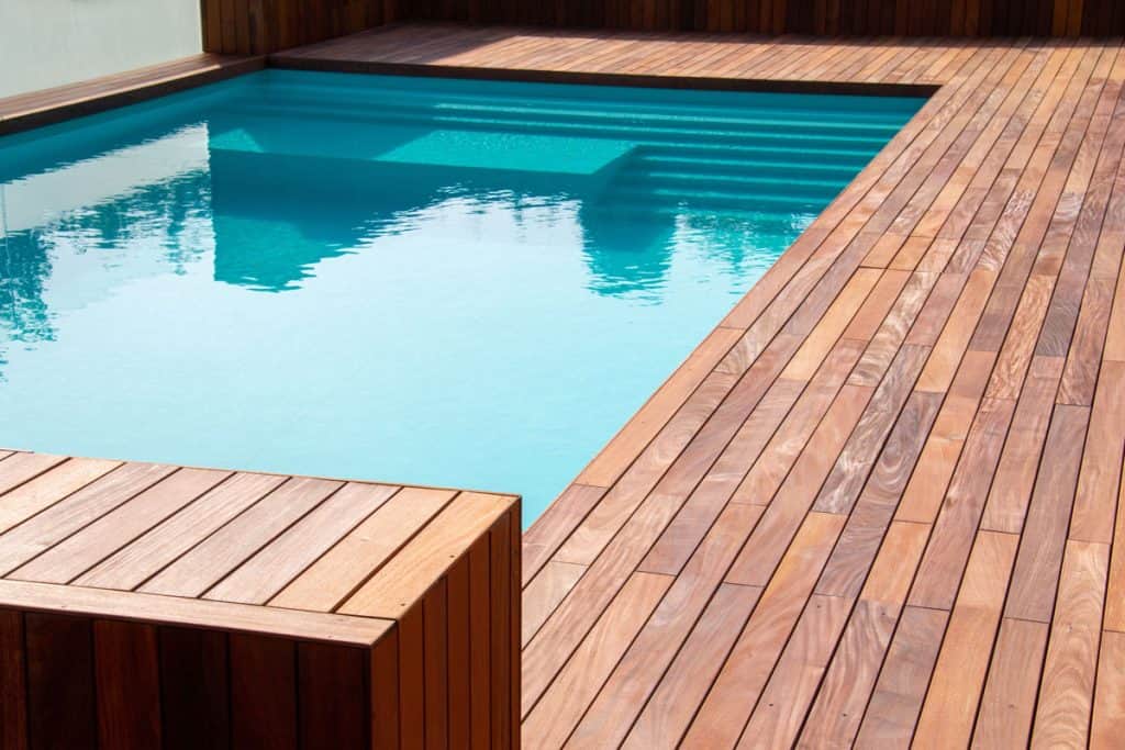 Red wooden deck with a pool on the side