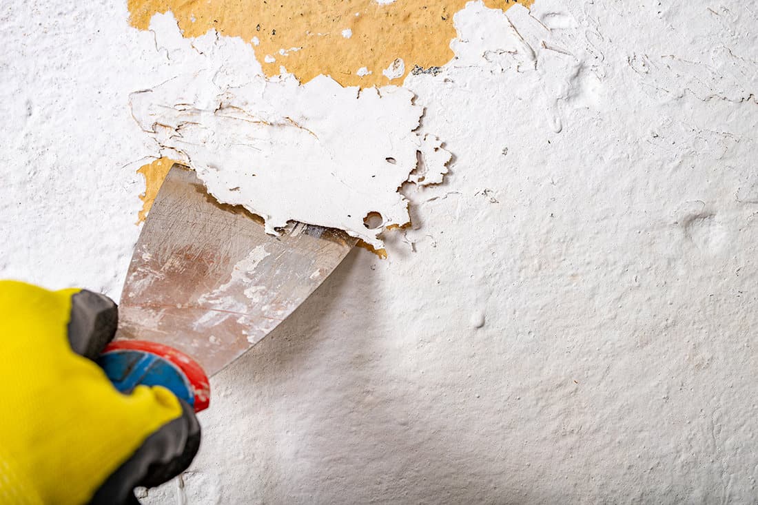 Removing old paint from the wall with a metal spatula