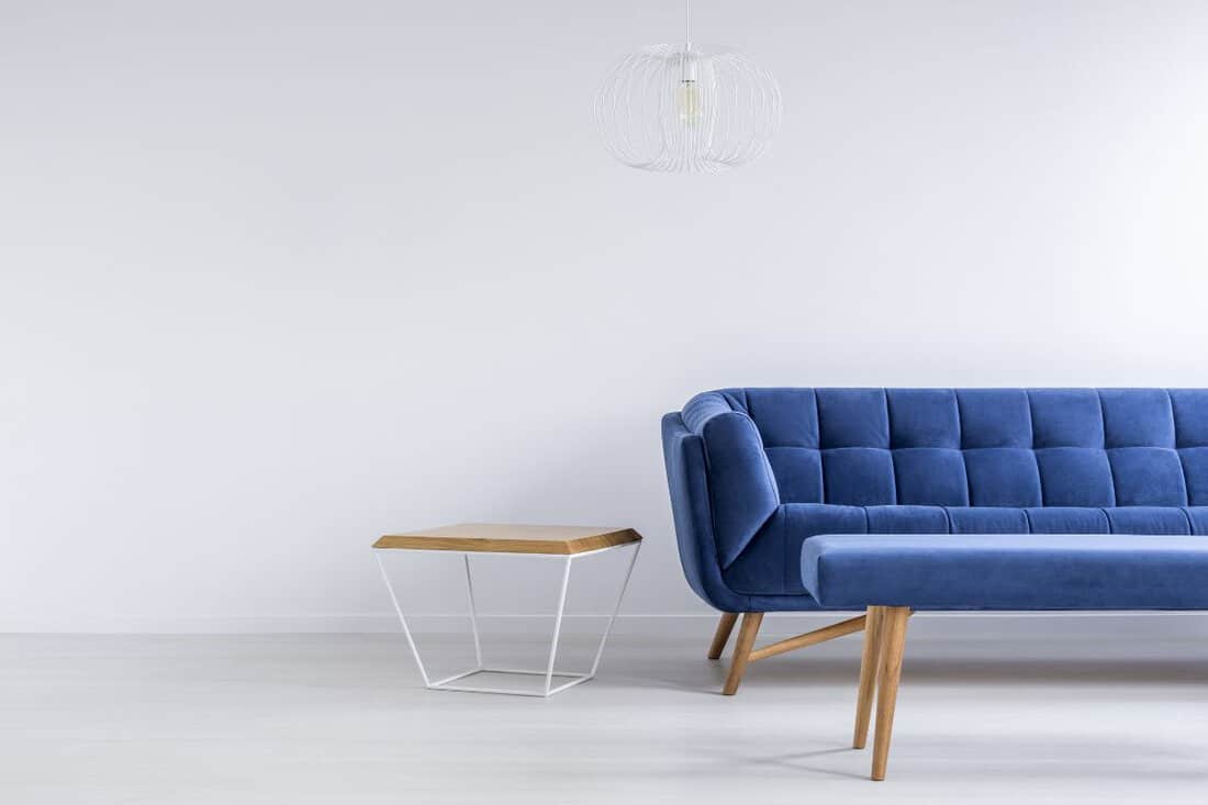 Room with blue sofa, bench, metal and wood table