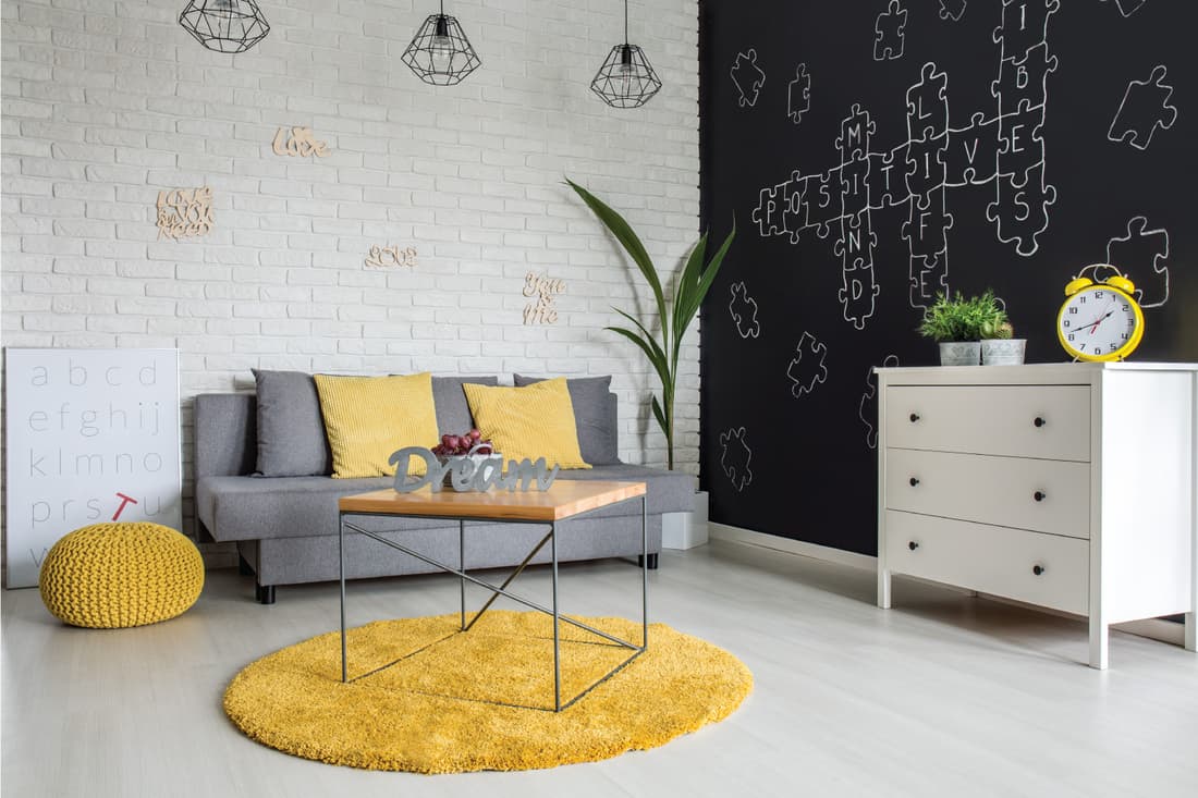 Room with sofa, dresser, blackboard wall and yellow details. fun space for kids