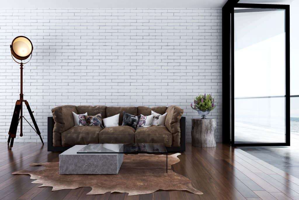Rustic themed living room with a dark rustic sofas, abstract carpet glass coffee table, and decorative brick walls