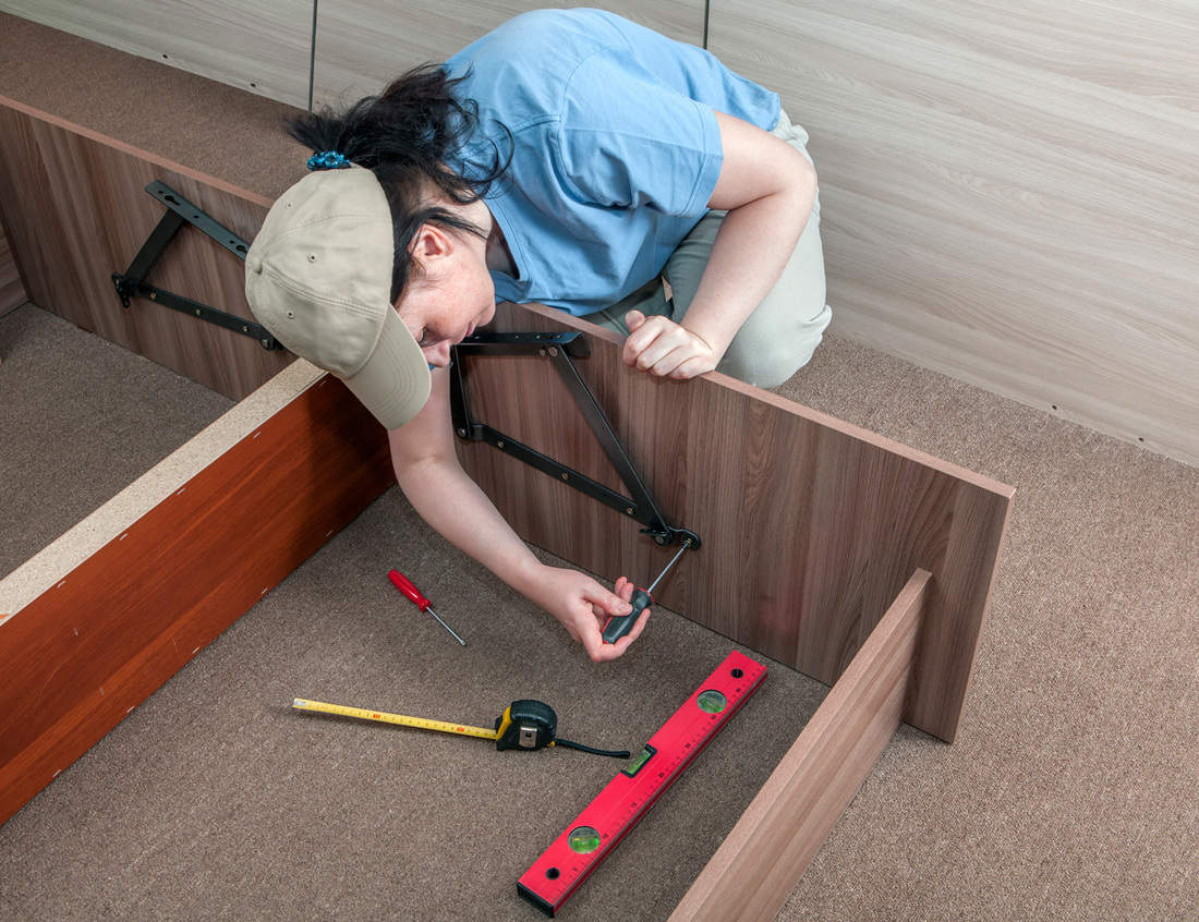 Self assembling furniture at home, woman housewife putting together assemble bed frame, using hand tools.