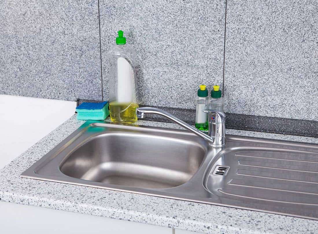 Silver kitchen sink with liquid soap and sponge