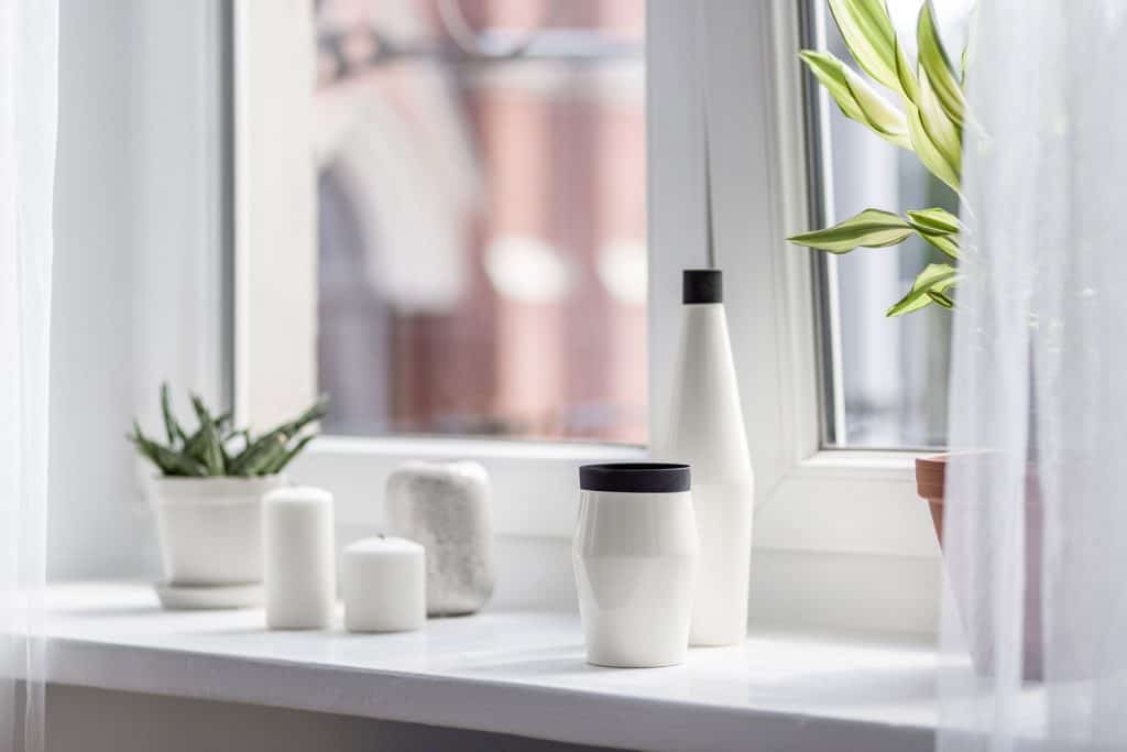 Small white vases and indoor plants placed on a table on the window