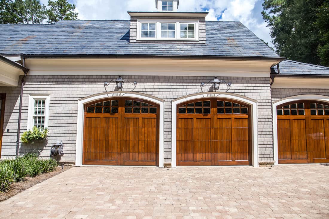 Portes de garage personnalisées en bois teinté pour grande maison du sud avec attrait extérieur