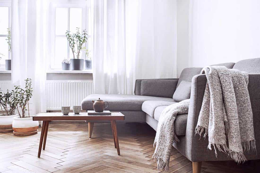 Stylish Scandinavian interior of living room with small design table and sofa