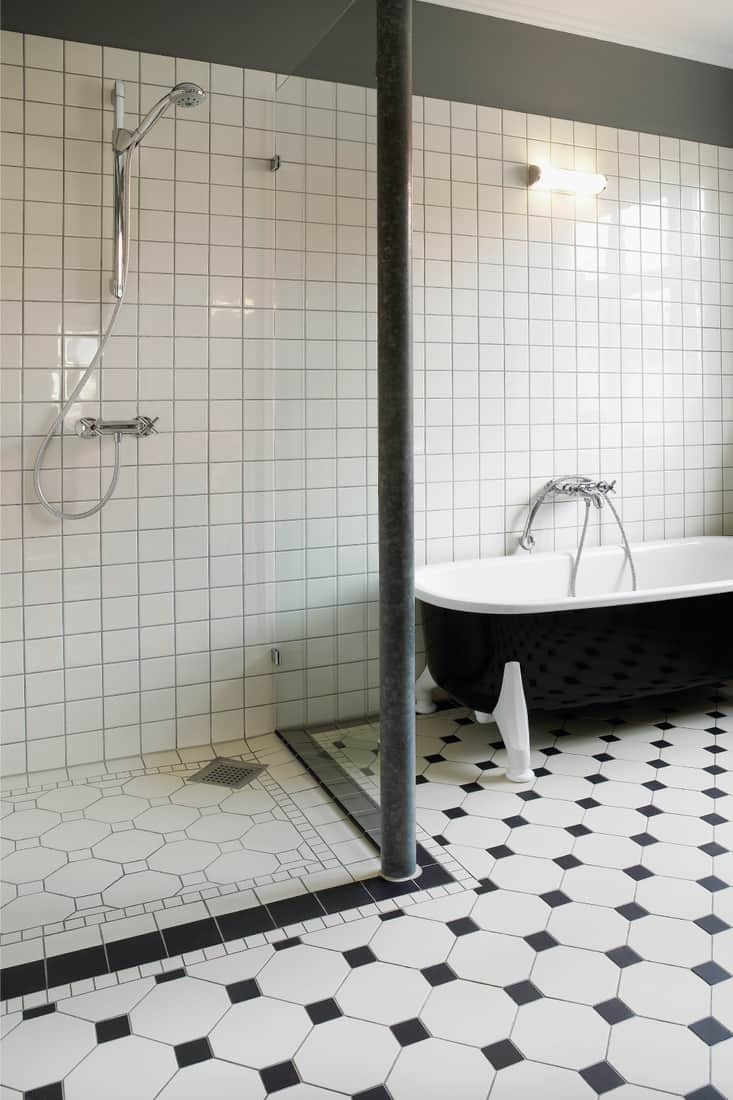 Renovated bathroom with shower cabin and bathtub, light cream colored tiles on floor and wall