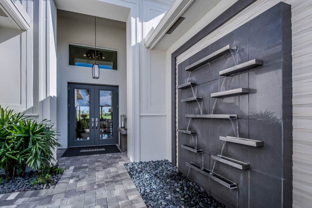 Ultra modern front porch with a decorative brick styled pavement and a water fall decorative area 