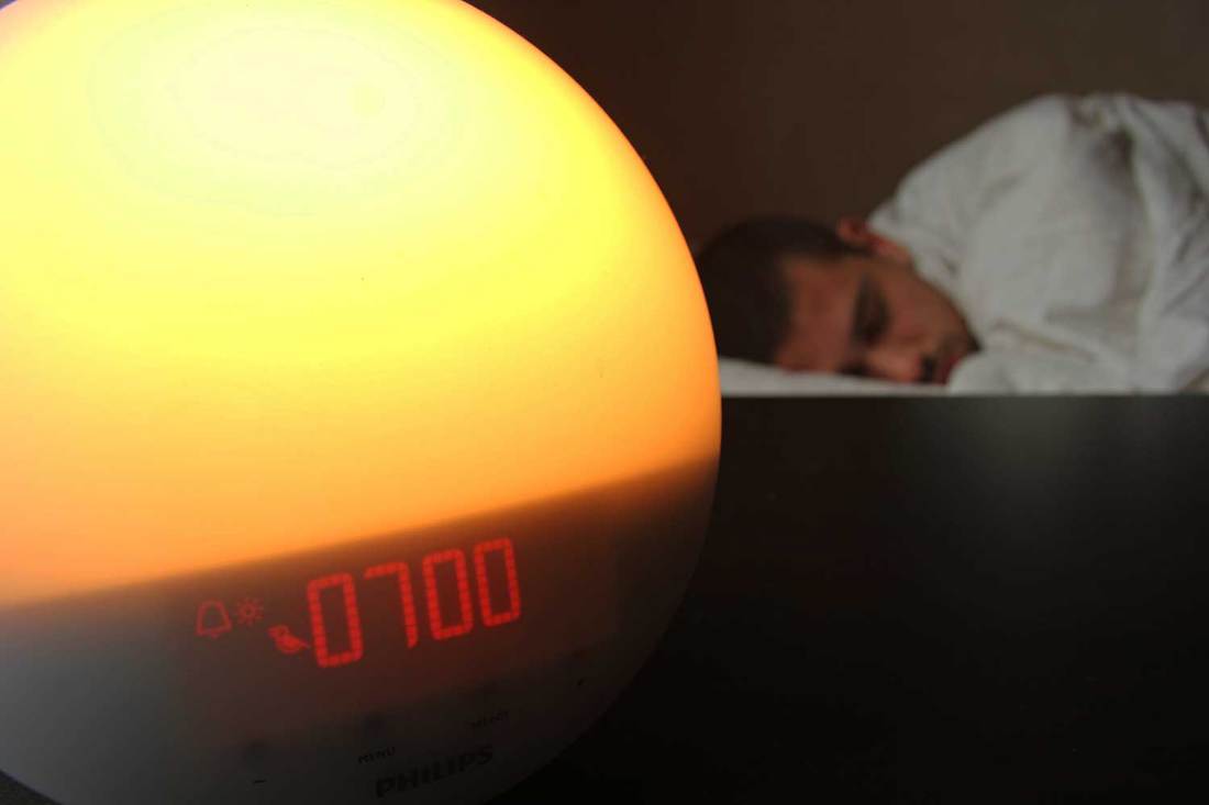 Wake up light alarm clock with sleeping person on the bed