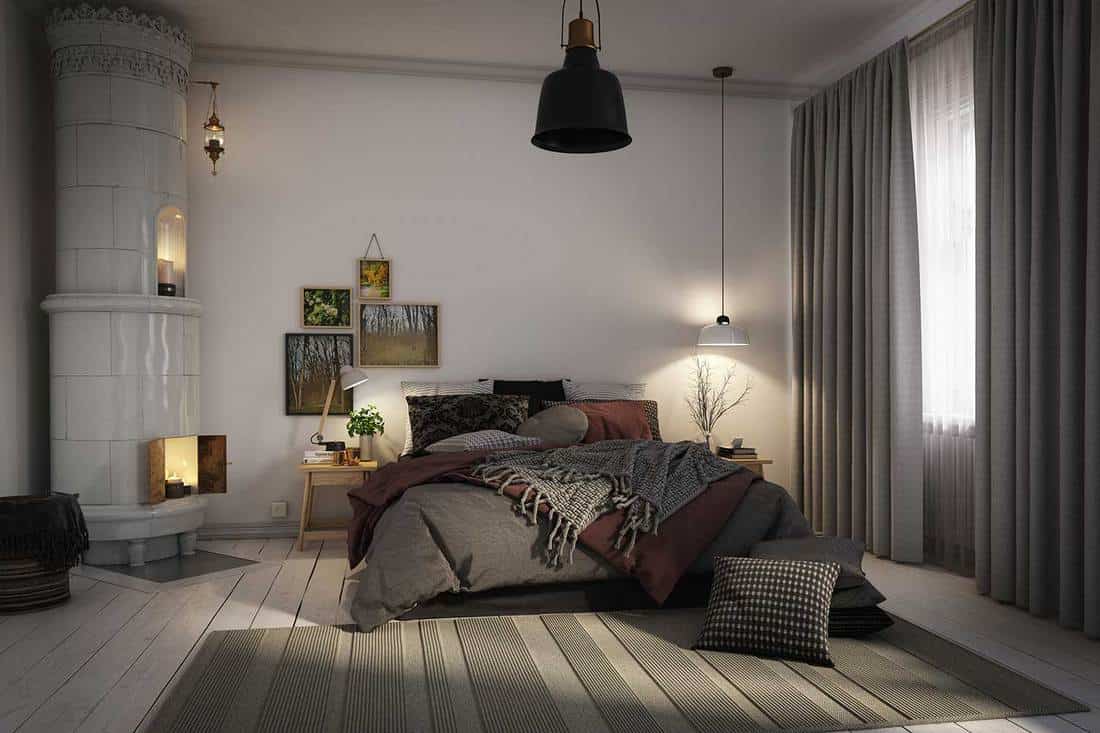 Warm and cozy Scandinavian style bedroom interior with fireplace and framed artwork on wall