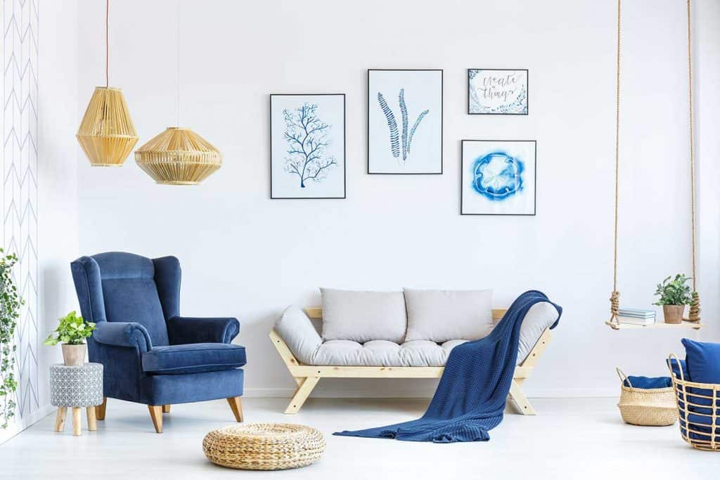 White and blue living room with sofa, armchair, lamp and posters