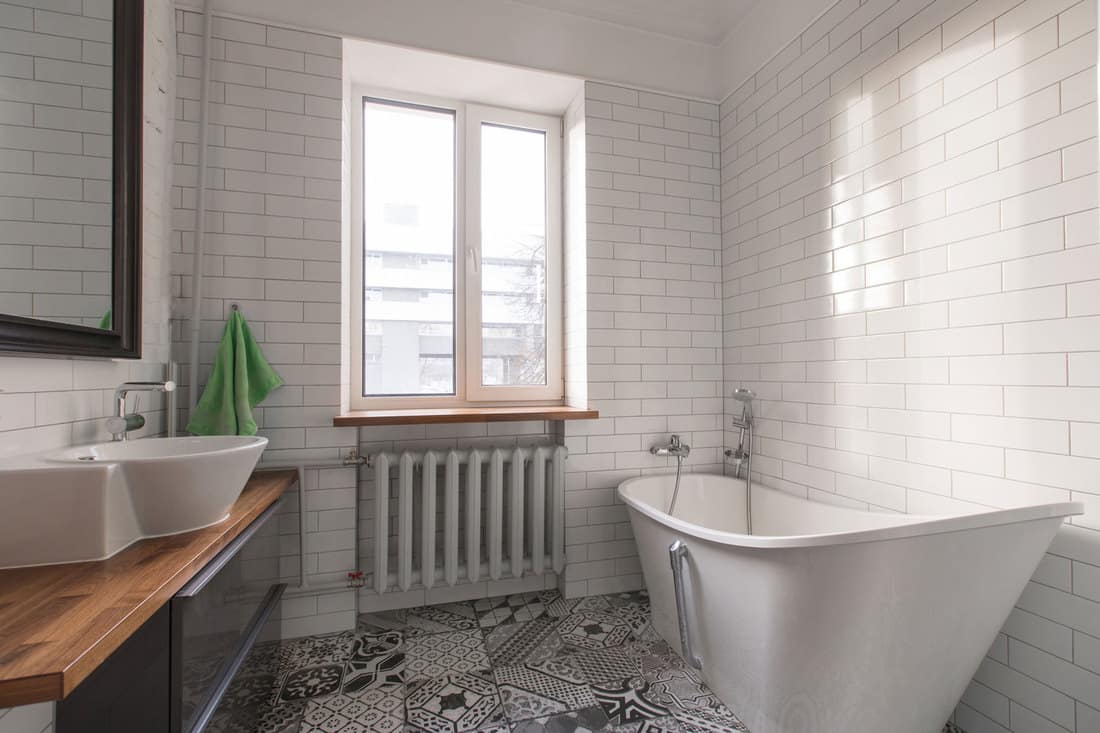 White beautiful attic bathroom in pastel gray and nude colours, with spectacular oval bath