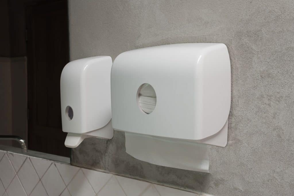 White dispenser mounted on a gray bathroom wall