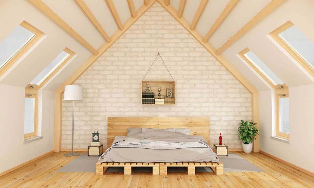 Wooden bed in attic bedroom with brick walls