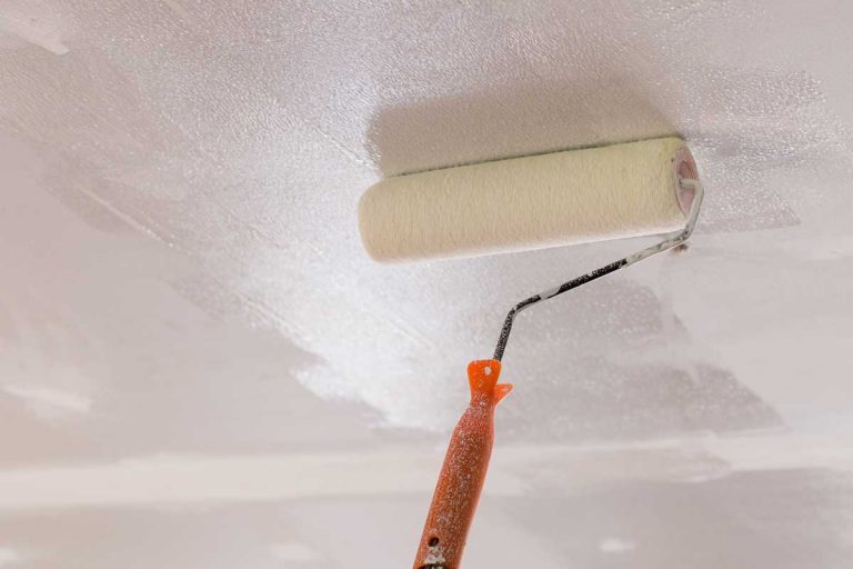 Worker using paint roller on the ceiling, How Long Does It Take To Paint A Ceiling?