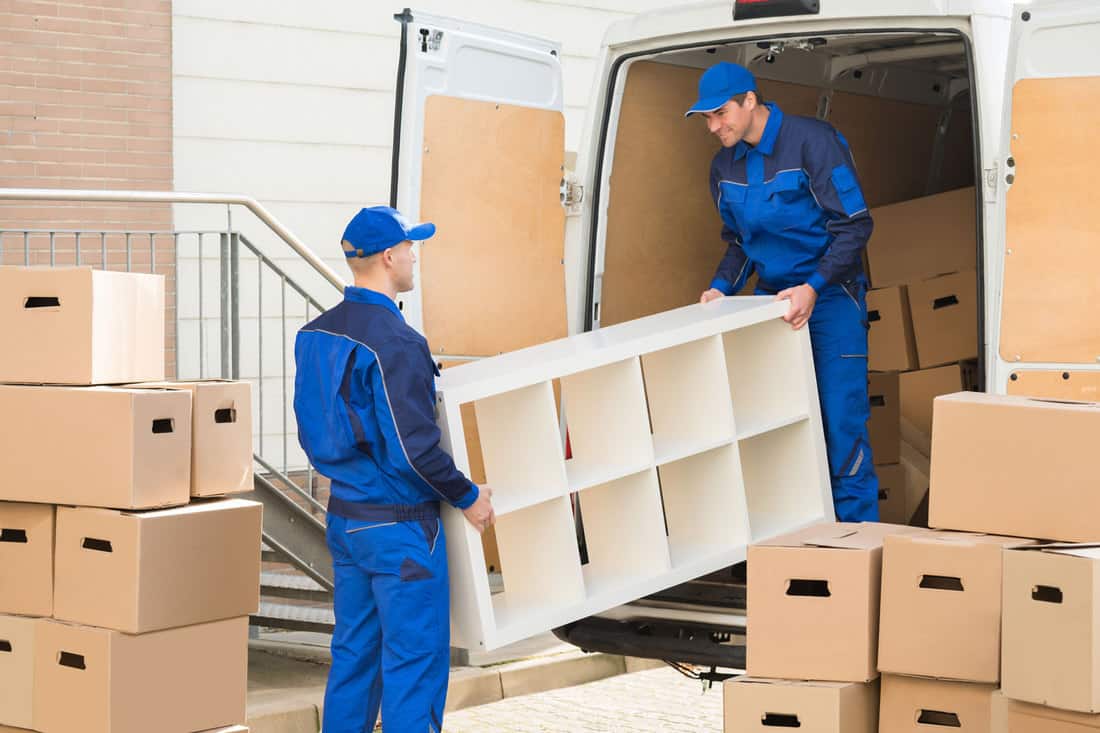 Young male movers unloading furniture and cardboard boxes from truck on street, Should You Tip Furniture Delivery Drivers?