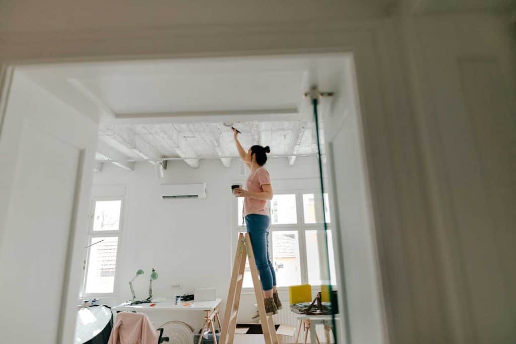 Young woman painting interior of apartment