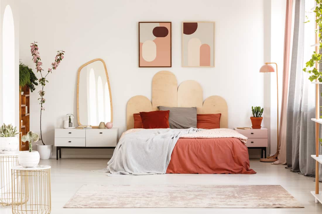 Bedroom with blush tone bedding, modern posters above bed with headboard