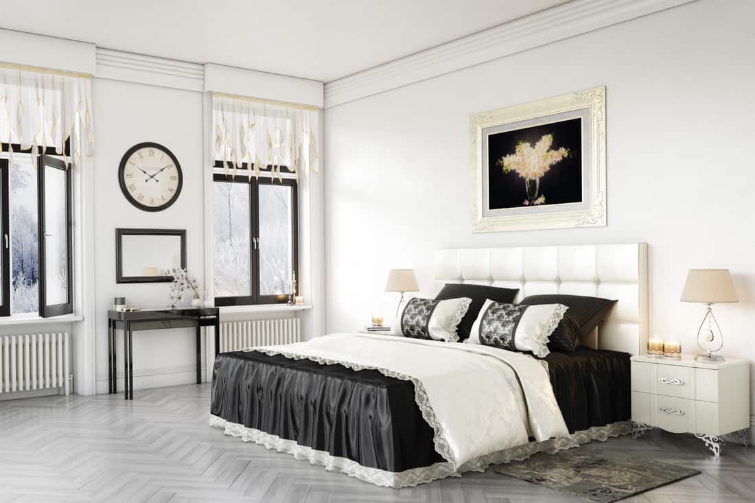 Bedroom with white bed frame and headboard, black bed sheet, white blanket and white walls