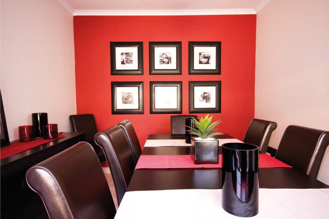 dining room with photo frames hung on a red colored wall. 11 Framed Wall Art Ideas For The Living Room