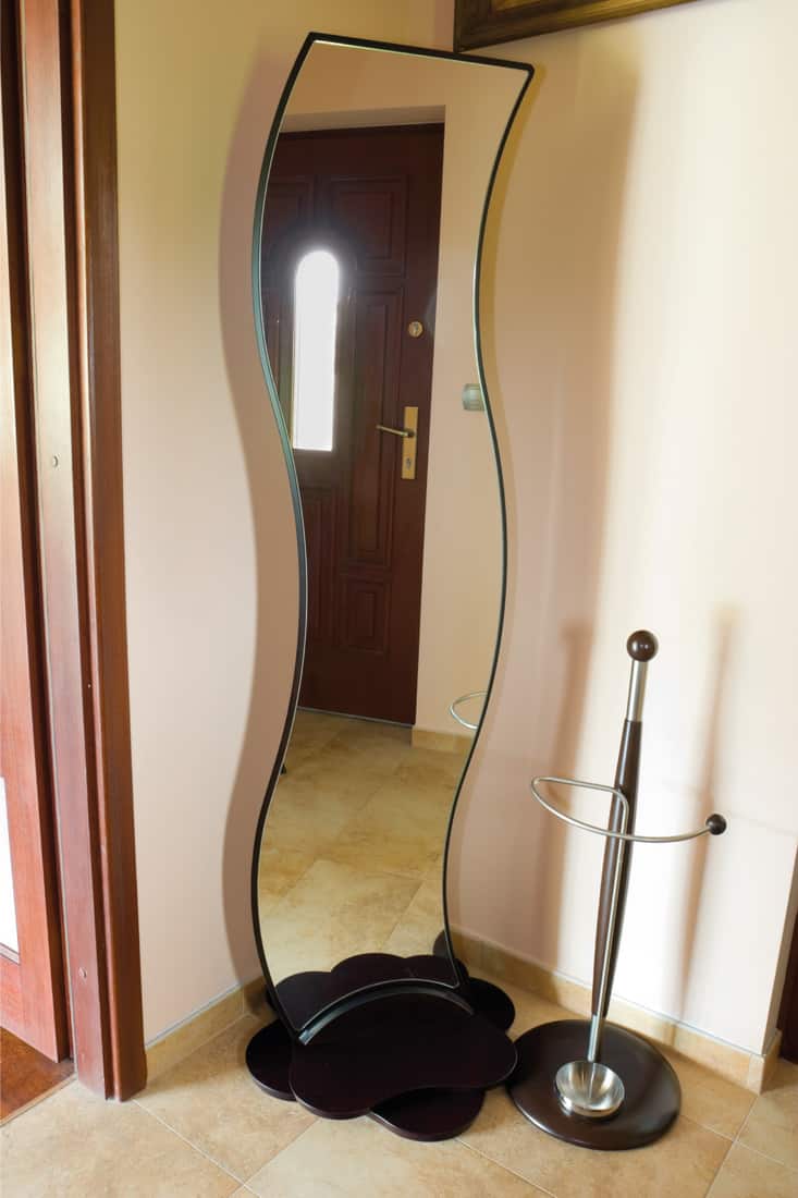 Eccentric shaped mirror on the corner of a foyer