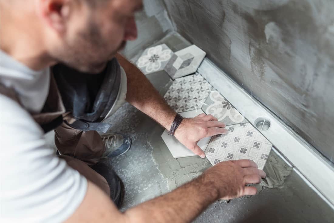 Male builder installing tiles on the bathroom floor, 17 Interesting Bathroom Floor Tile Ideas