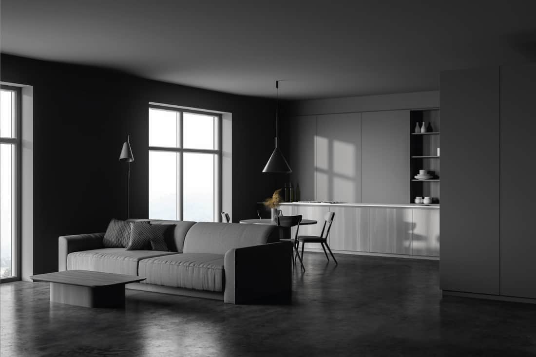 kitchen and living room with gray walls, concrete floor, dark wooden countertops and cupboard, round dining table and cozy sofa. What Colors Go With Charcoal Grey Couch