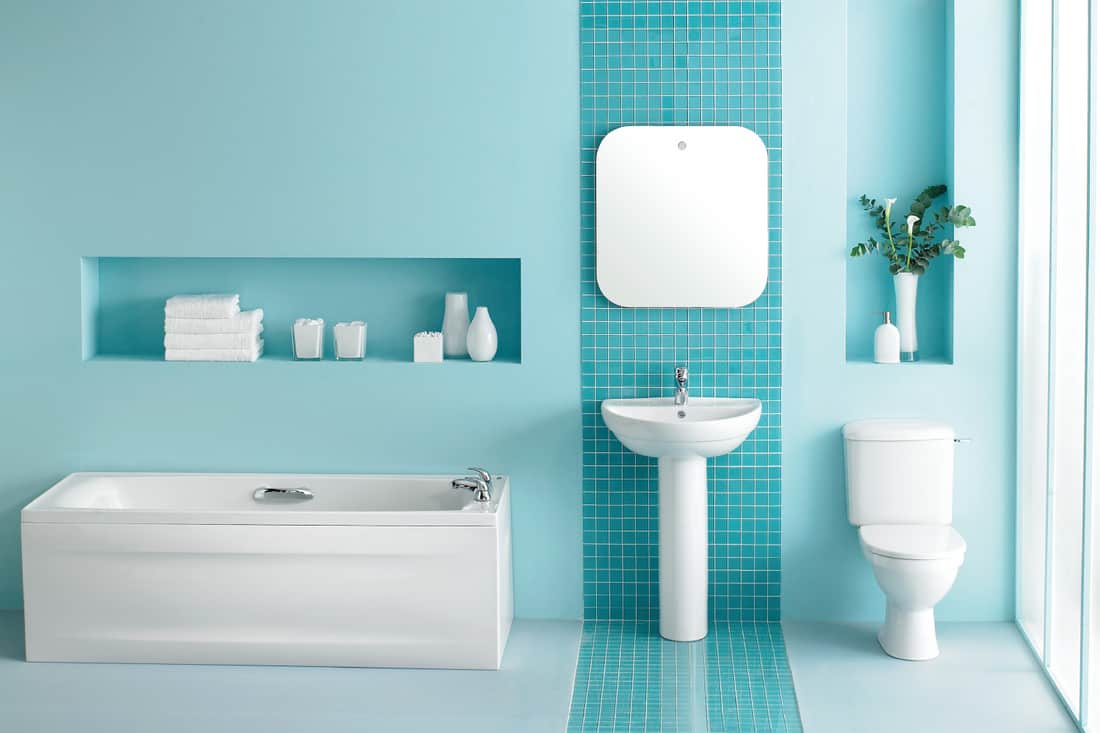 Large luxurious bathroom in turquoise blue with a stripe of blue mini tiles in the middle