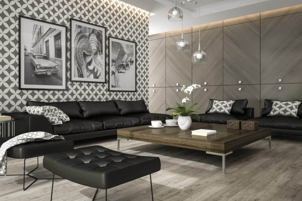 Salon avec papier peint élégant, canapé noir, table centrale et photographies encadrées