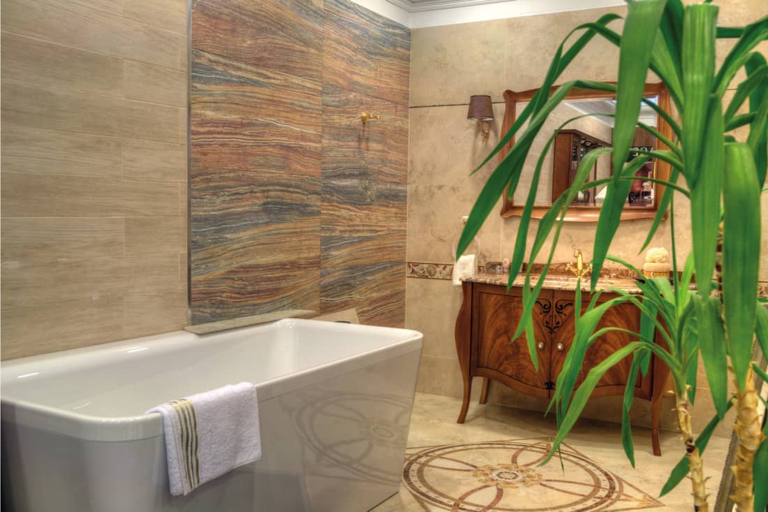 Luxury bathroom with floor tile mural, large bathtub and sink with vanity mirror