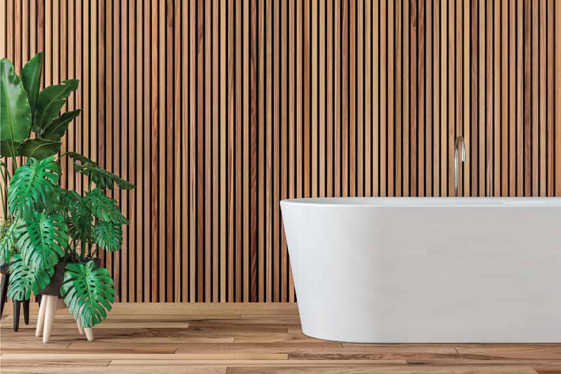 modern bathroom with hardwood parquet floor and wooden paneled wall, free standing bathtub, potted plants on the side. 13 Perfectly Zen Bathroom Ideas