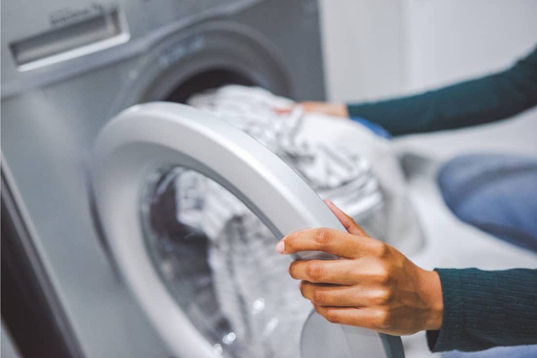 woman using a washing machine to do laundry at home