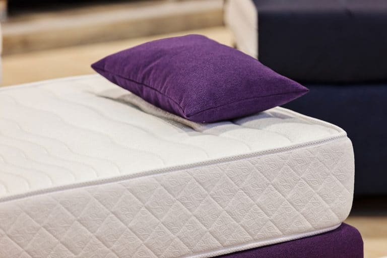 A comfortable and thick mattress with a purple colored pillow on top, Is A Mattress Considered Furniture?