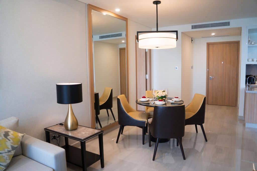 Un appartement de salon à thème contemporain avec un ensemble de salle à manger luxueux, un canapé armé carré et un immense plafonnier dans la salle à manger
