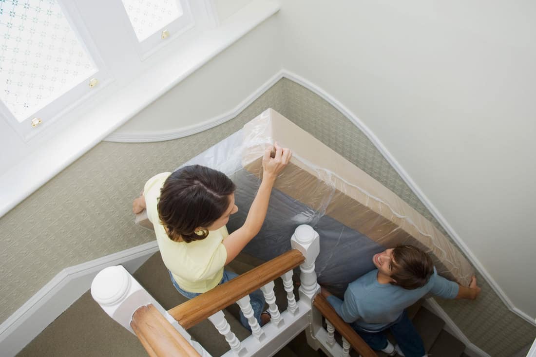 A couple moving a mattress up a narrow stairway, Can You Bend A Mattress To Get It Upstairs?