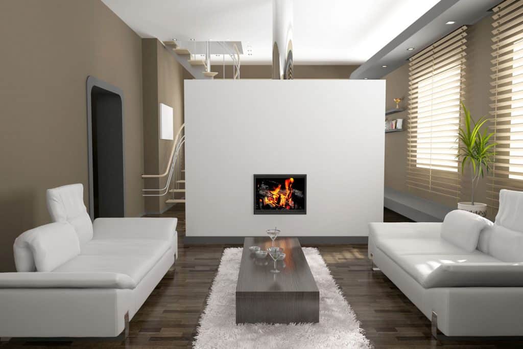 A dark brown colored wall living room with white sofas, and a white wall center fireplace