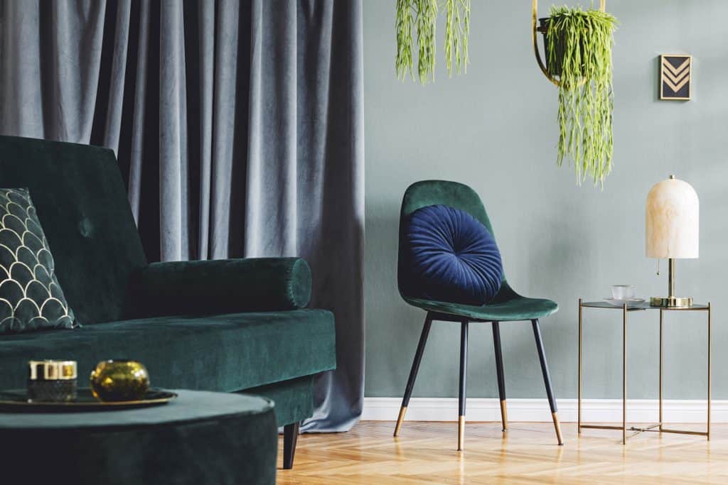 A dark green teal themed living room with dark teal furniture's and hanging plants inside