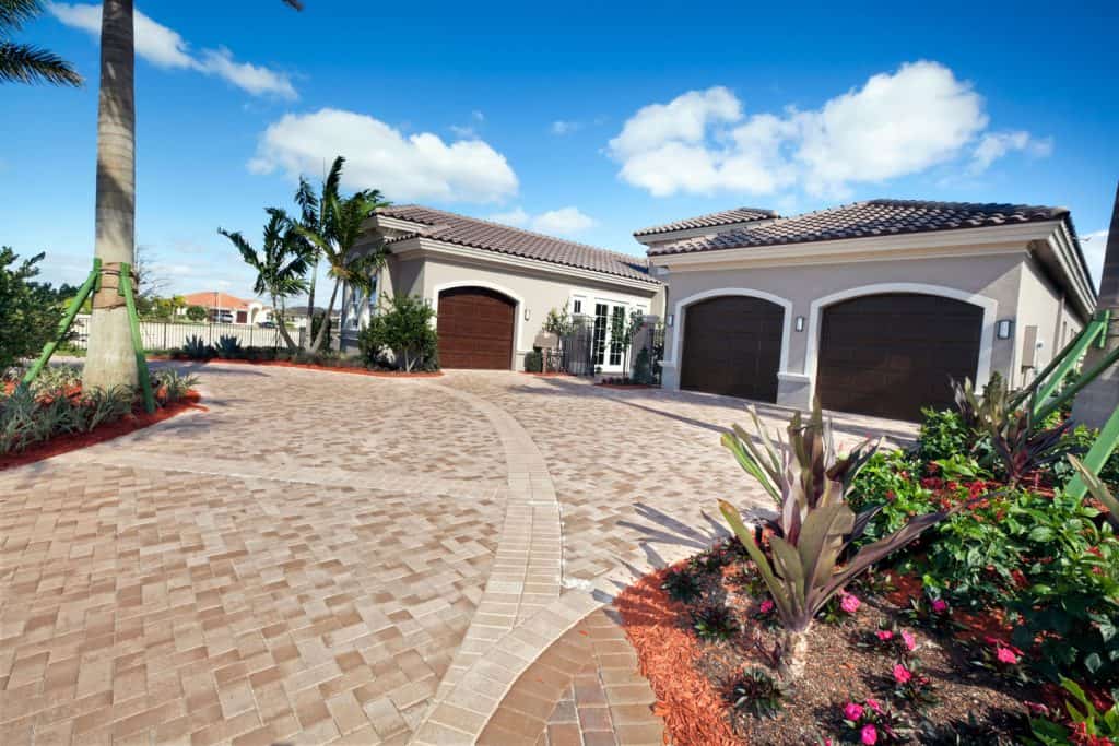 A gorgeous driveway with a house with two way garage door and a paver driveway