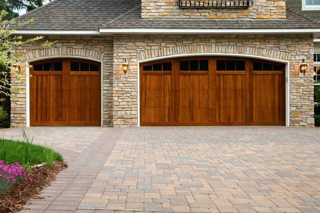 A gorgeous house with decorative stones on the wall and a huge brown colored garage door