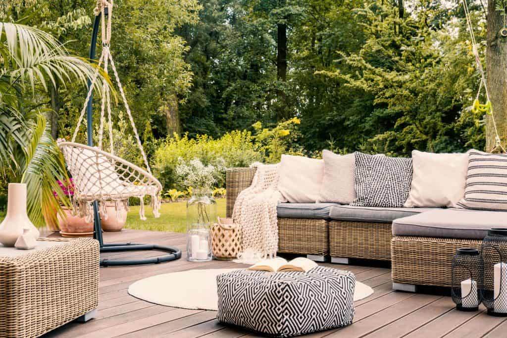 A gorgeous outdoor patio with a long rattan sectional chair with throw pillows