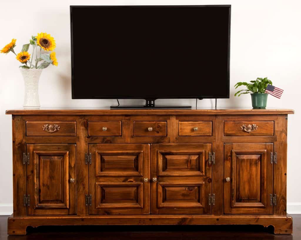 A huge wooden cabinet with TV on the top and indoor plants on the side