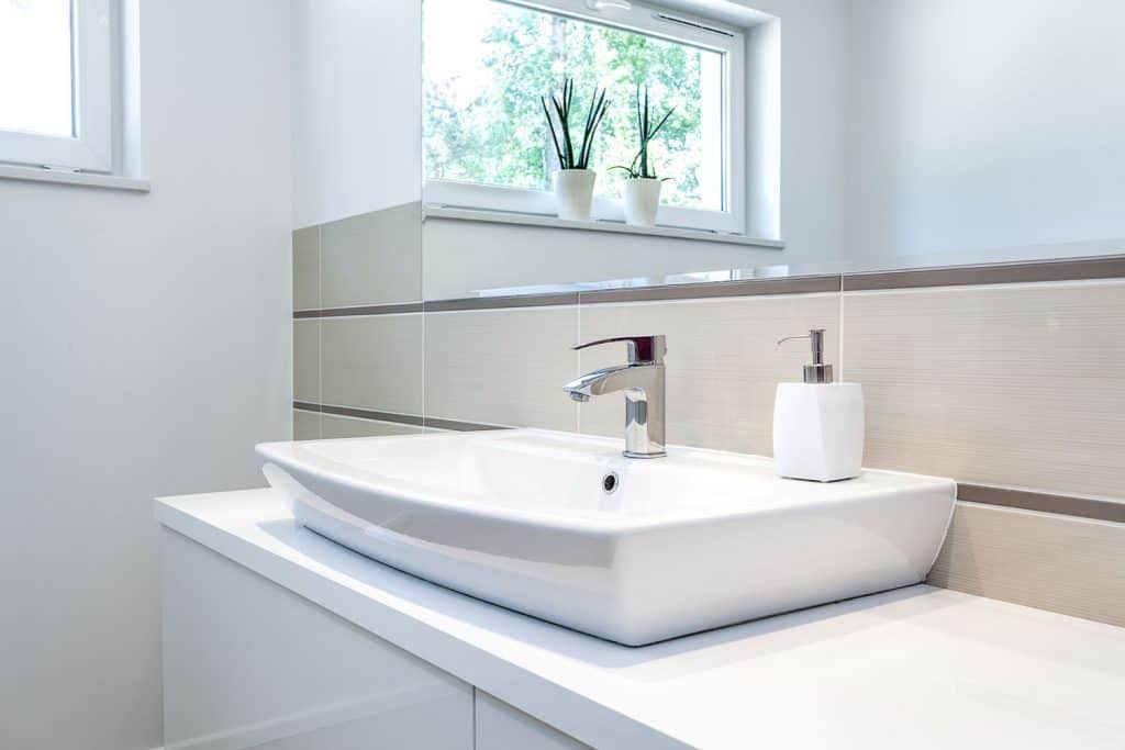 A modern vanity area with white ceramic lavatory's and white bathroom