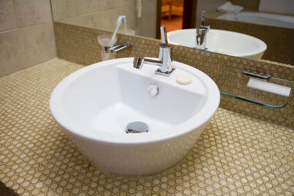 A wedge designed lavatory with small circular decorative vanity tiles