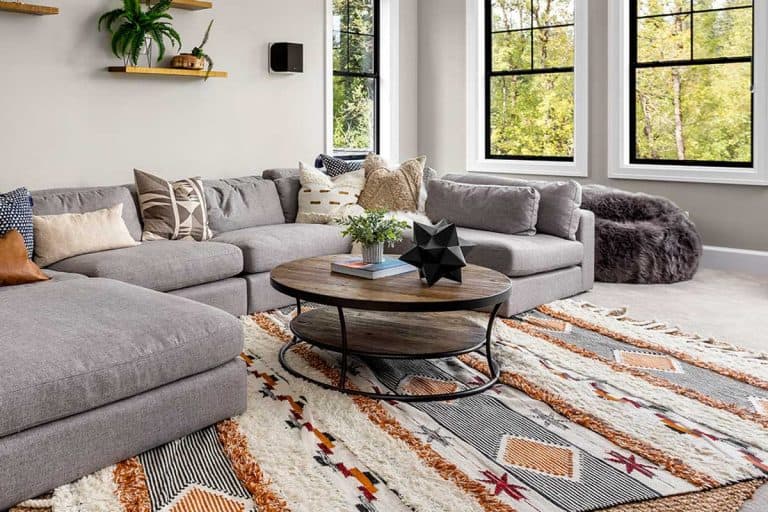 Beautiful living room interior with colorful area rug, large couch, and abundant natural light, Do Ruggable Rugs Curl? [And How To Keep Them Down]